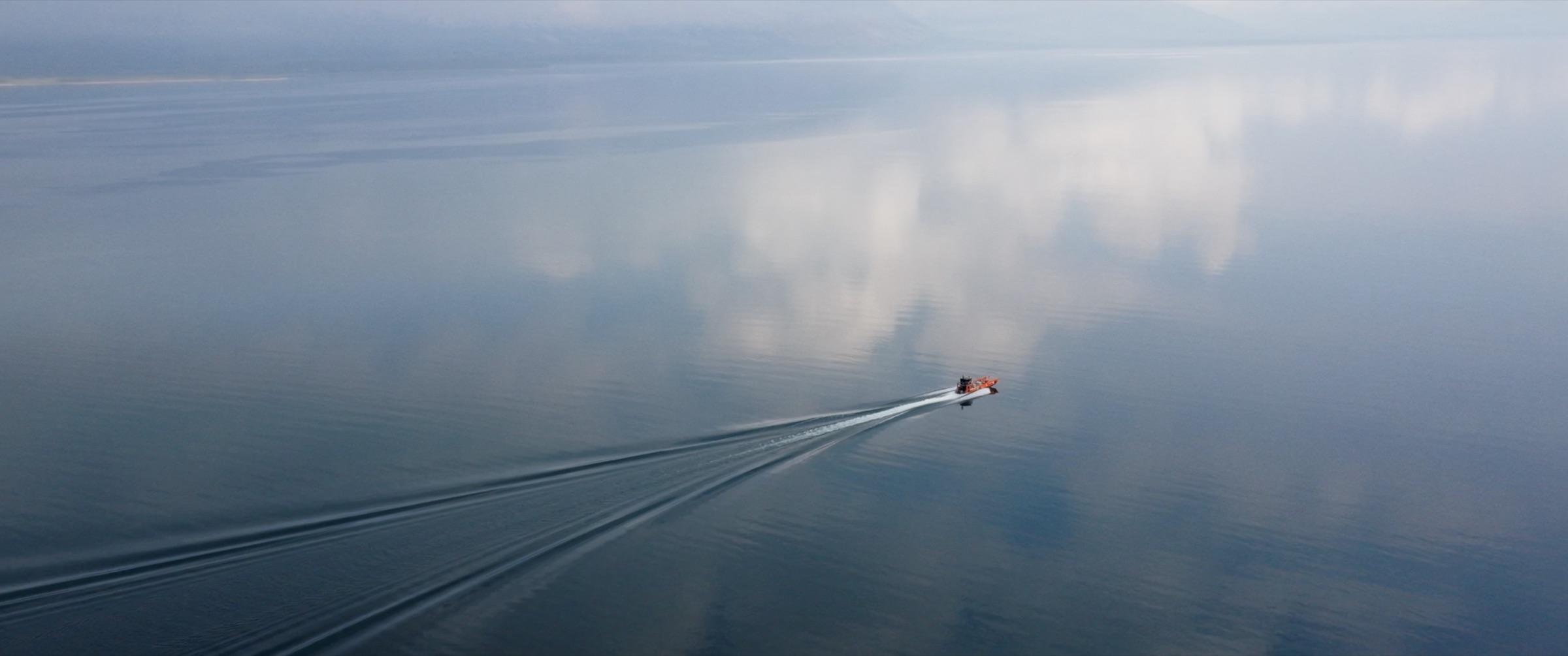 A small motorboat leaving a wake across still water