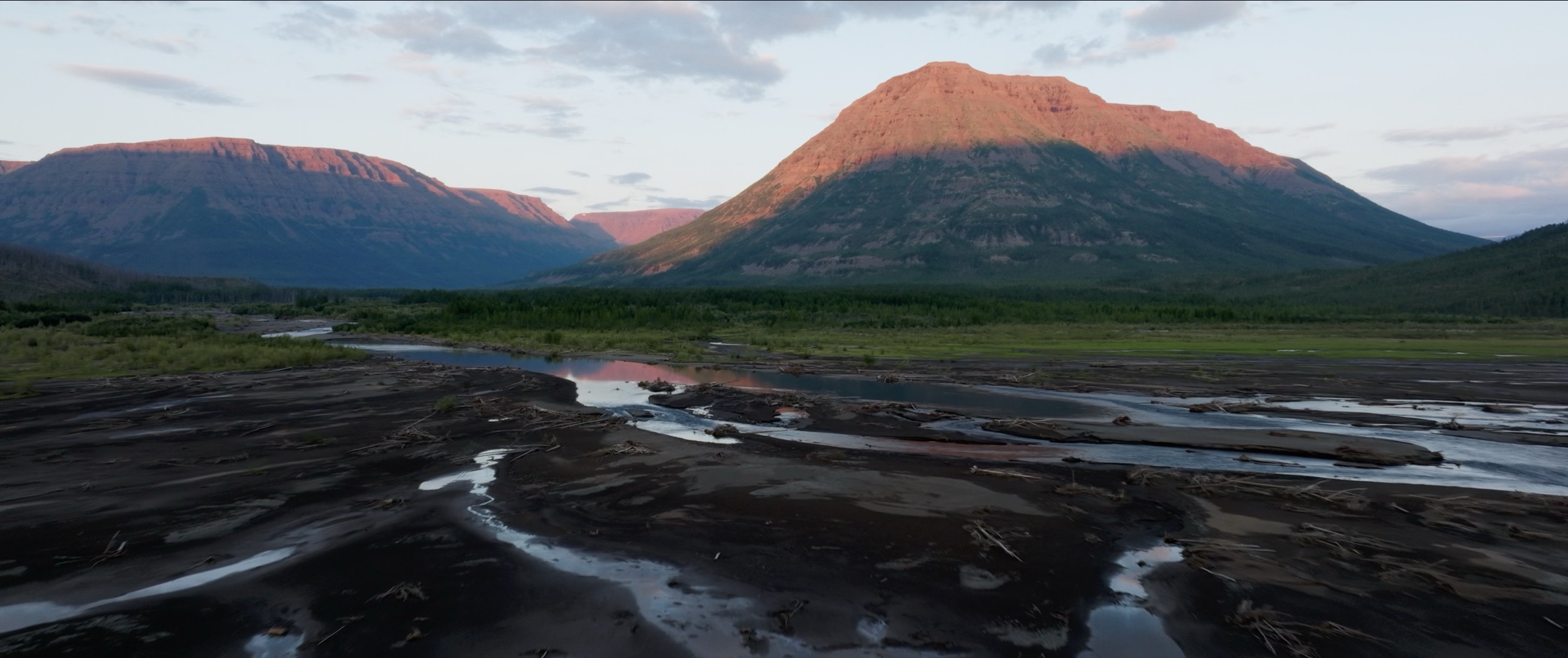 Mountain lit by evening sun above a river valley